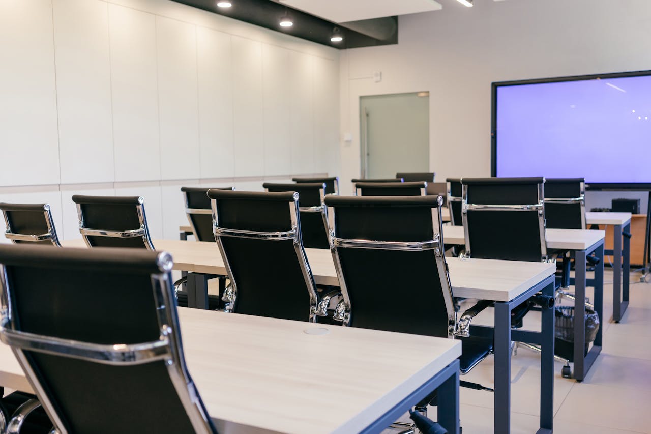 our-story Spacious, modern conference room with black chairs and a projection screen.